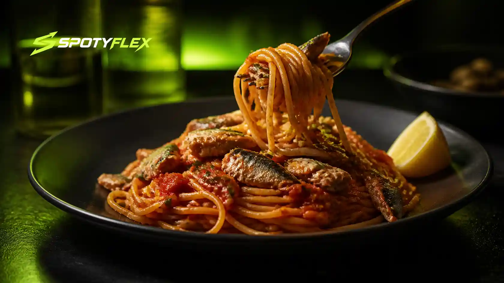 A plate of tomato pasta with flaked sardines and a lemon wedge.