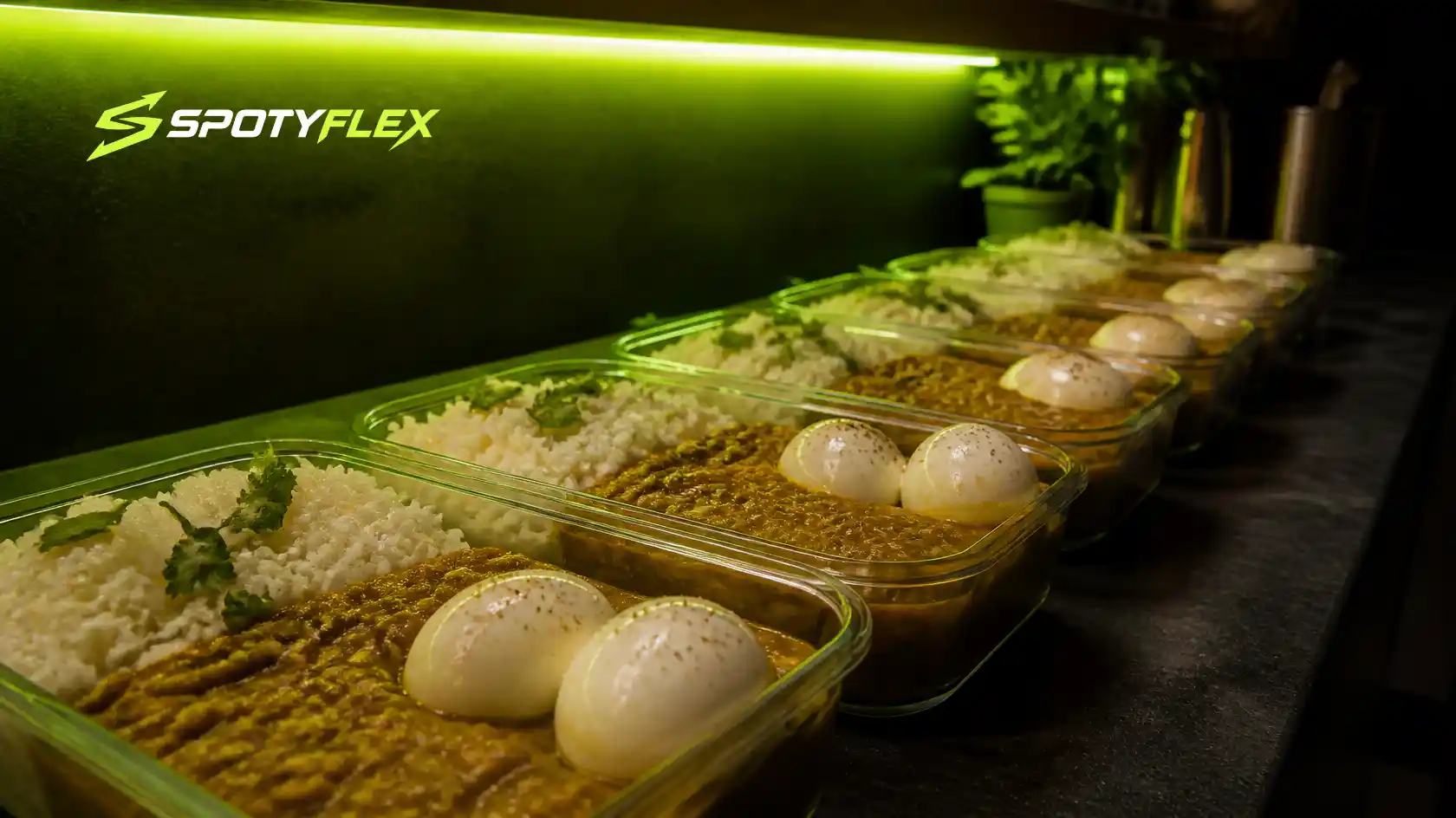 Meal prep containers filled with rice, soup and boiled eggs on a dark counter.